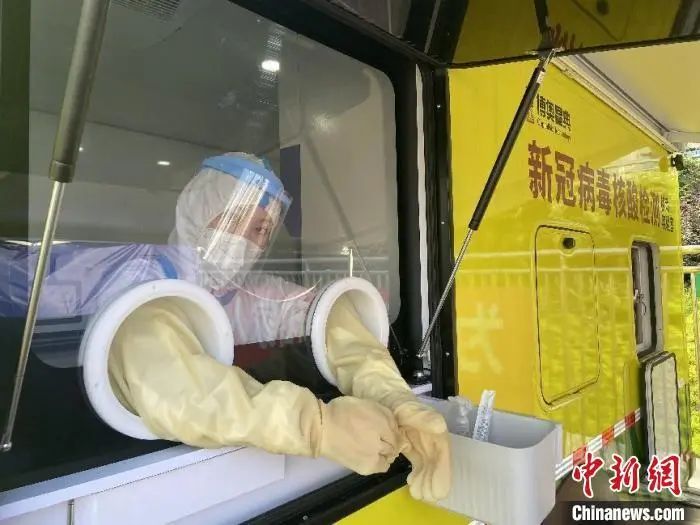 资料图:新冠病毒核酸检测“小黄车”的工作人员正在开展核酸采集工作。 陈晟 摄